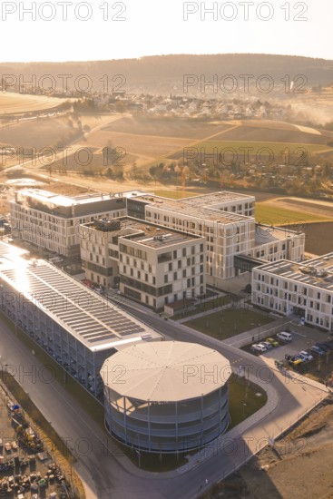 Modern buildings with solar panels in an urban environment surrounded by picturesque fields, new