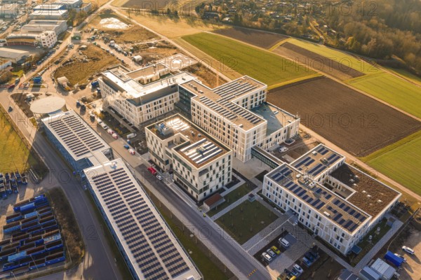 Modern buildings with solar panels surrounded by agricultural fields and industrial areas, new