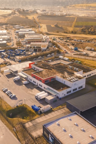 Industrial complex with warehouses and vehicles on the outskirts of a city, new hospital on the