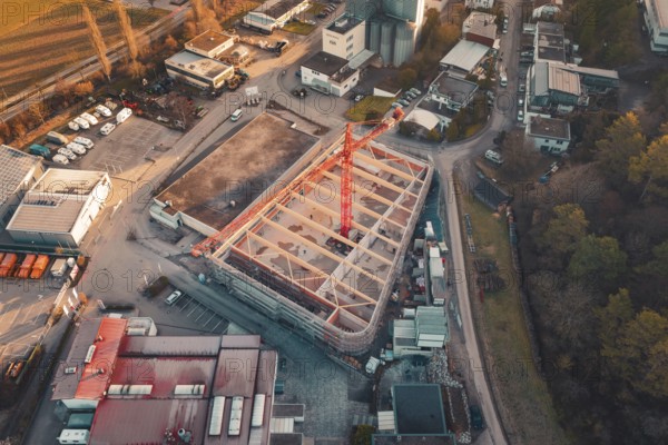 Aerial view of a construction site with crane in an urban area at sunset, surrounded by buildings