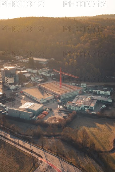 View of an industrial landscape with construction crane and buildings at the foot of wooded hills