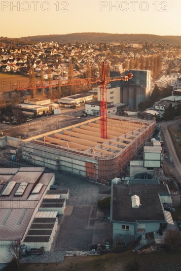 Industrial area with crane and new buildings in sunset light, on the edge of a city in a hilly