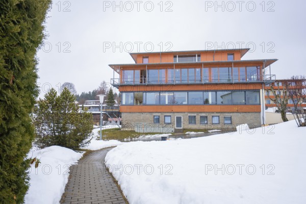 Modern building in snowy landscape with clear skies and surrounding trees, specialist clinic for