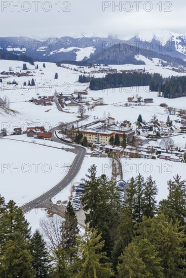 Snowy village in the mountains with a winding road surrounded by trees and cloudy sky, specialist