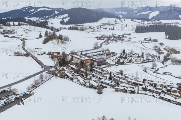 Wintery mountain village surrounded by snow-covered roads and mountains taken from the air,