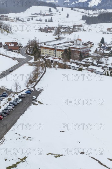 Snow-covered village with parking space in the midst of a winter landscape seen from the air,