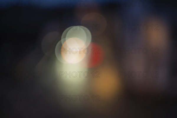 Colourful lights illuminate the city street at night. The scenes are blurred and there is movement.