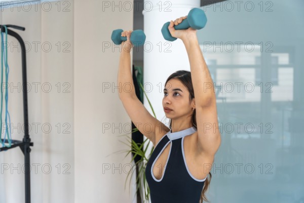Young woman performing a strength workout with dumbbells, focusing on rehabilitation and medical
