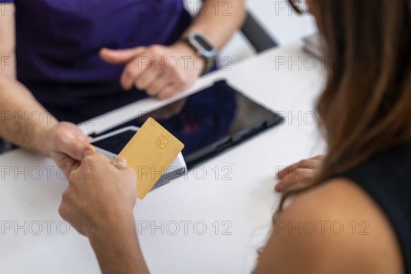 Patient paying medical bill with a credit card at a clinic reception, completing a healthcare