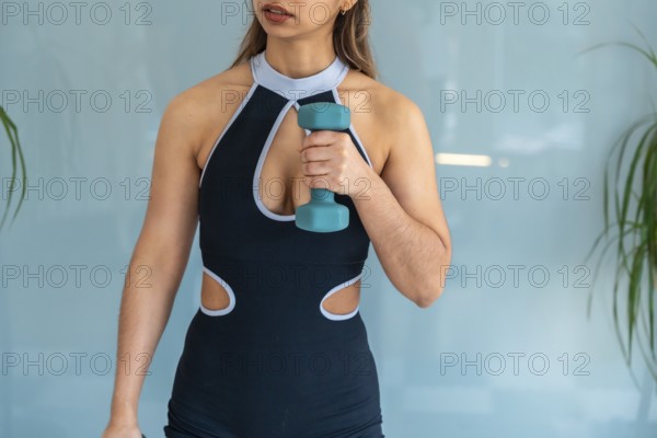 Young woman working out with a light dumbbell, focusing on strength and flexibility during a