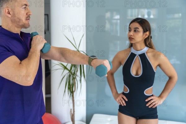 Male physiotherapist guiding a young female athlete through a rehabilitation exercise, holding