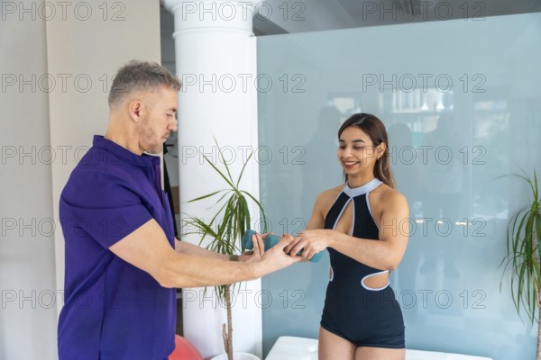 Physiotherapist explaining a rehabilitation exercise to a smiling young woman, holding light