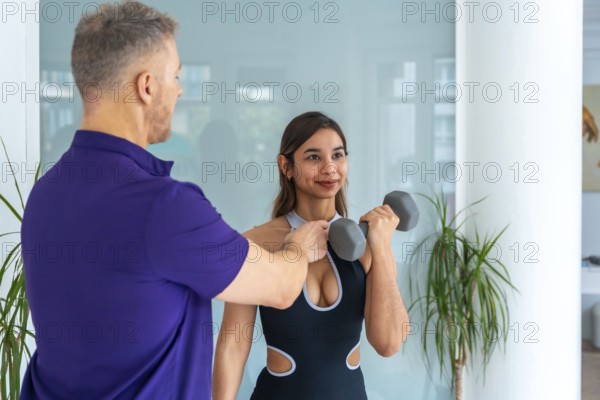 Physiotherapist male trainer assisting a young woman client with rehabilitation and strength