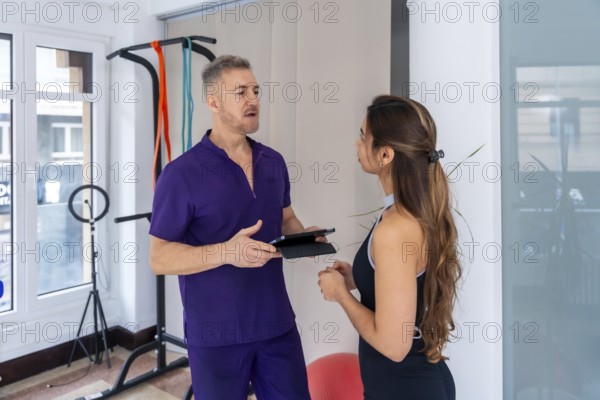 Male physiotherapist discussing rehabilitation and wellness strategies with a young female patient