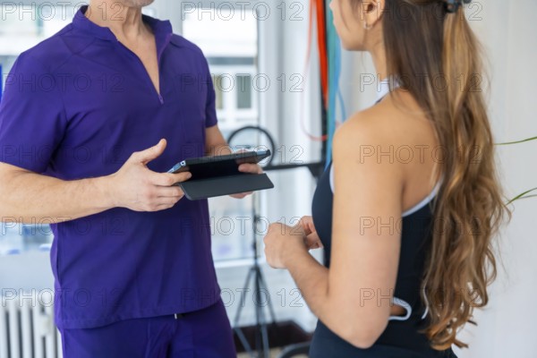 Physiotherapist wearing purple scrubs discussing a medical recovery or sports osteopathy therapy