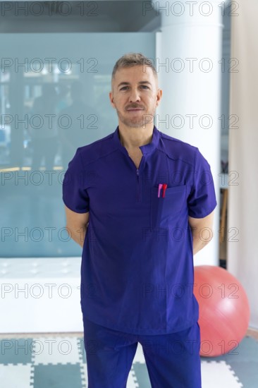 Professional physiotherapist wearing a purple scrub uniform is standing confidently in a modern