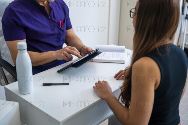 Professional osteopath or physiotherapist doctor in medical scrubs consulting a female patient,