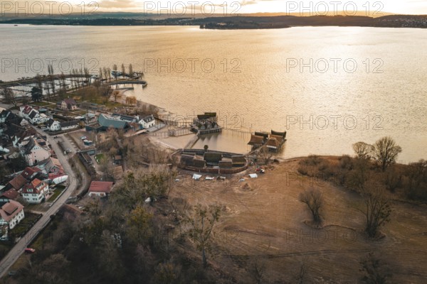 Extensive view with a lake, traditional stilt houses and warm sunset light, stilt houses