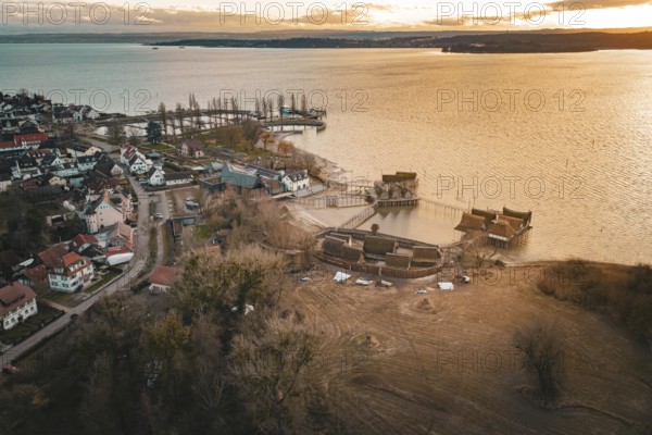 Panorama of a village with stilt houses on the lakeside at sunset, captured in warm light, stilt