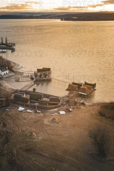 Historic stilt houses on the shore of a lake at sunset with warm light and peaceful atmosphere,