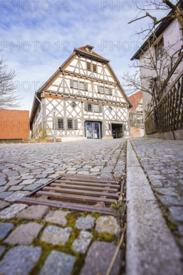 Half-timbered house with cobblestone street and wooden fence in a historic setting, Ötisheim,