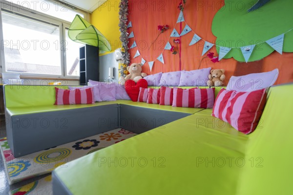 Cosy seating area with colorful pillows and cuddly toys, decorative background, homework
