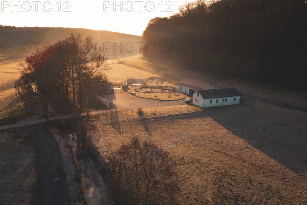 Sewage treatment plant in a meadow surrounded by trees at sunset, rural and peaceful atmosphere,