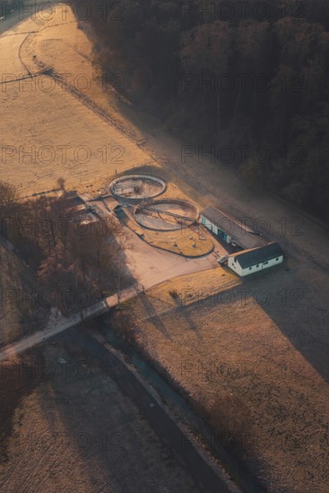 Wastewater treatment plant and delicate light patterns through trees and fields at dawn, Gechingen,