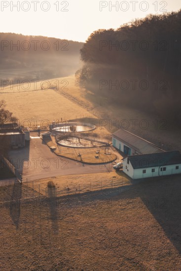Wastewater treatment plant in a rural area in morning light with long shadows and light fog,