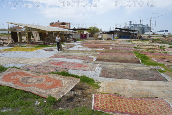 Open-air market with a variety of carpets spread across grasses and pebbles, Aksaray province,