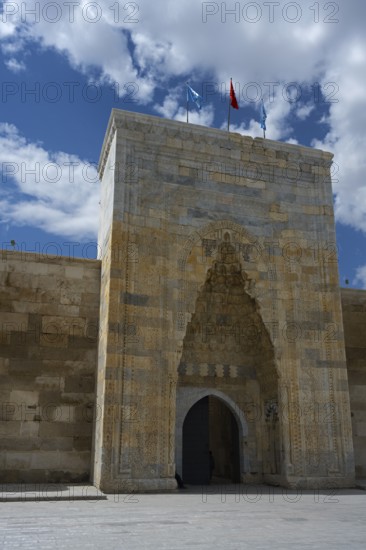 Decorated medieval gate in a high stone wall under a clear sky, richly decorated portal of the