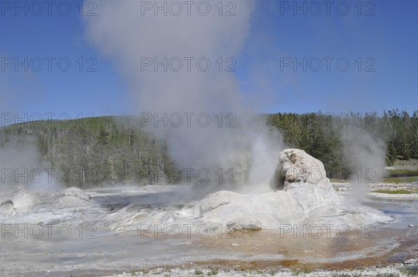 A geyser emits steam surrounded by rocks and natural landscape, Yellowstone National Park, Wyoming,