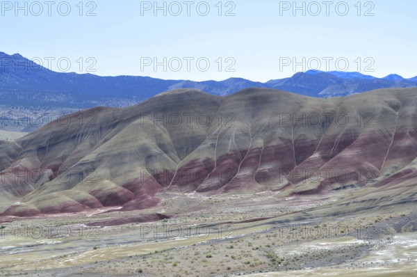 Colourful hills with red stripes under clear skies. Impression of an eroded geological formation,