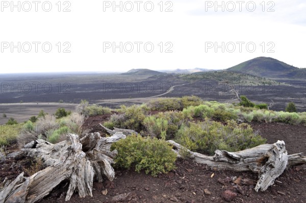 Wide, rocky lava rock plain with grasses and distant hills, Craters of the Moon National Monument,
