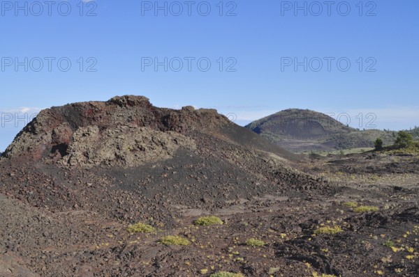 Landscape with volcanic hills, lava rock, sparse vegetation and clear sky, Craters of the Moon