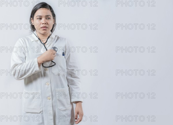 Asian Female Doctor Listening to Her Own Heartbeat with Stethoscope isolated. Young female doctor