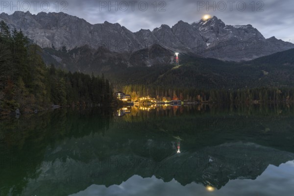 A stunning night view of Eibsee, surrounded by the Bavarian Alps The illuminated village reflects