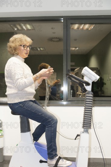 A mature woman performs a spirometry test to assess her lung function in a hospital setting, using