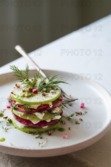 From above view of a gourmet salad featuring layers of green cucumber, red beetroot, and white