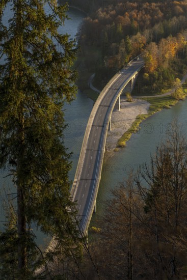 A picturesque Faller-Klamm Bridge gracefully arches over a serene river surrounded by vibrant