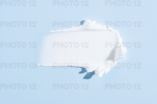 High-quality image showcasing a smooth, white cream smear isolated on a serene blue background,