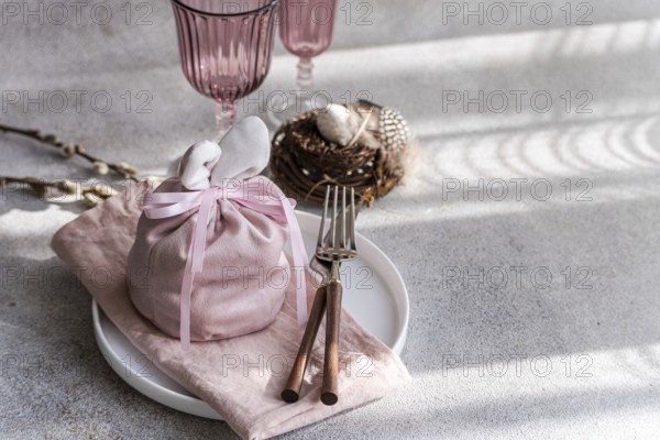An artistic Easter table arrangement featuring a bunny-themed pink cloth wrap, elegantly tied,