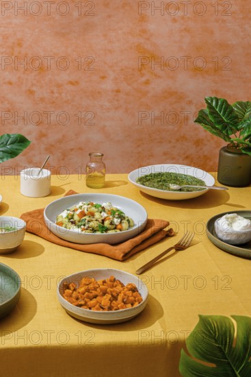 Lavish Italian dinner spread featuring bowls of basil pesto gnocchi, a fresh green salad, sweet