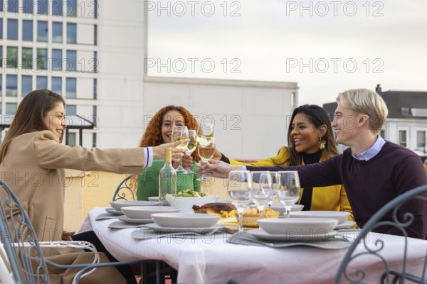 A joyful group of friends toasting with wine glasses on a rooftop The table is elegantly set,