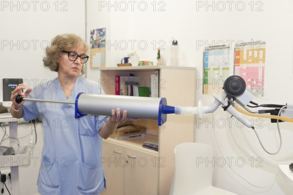 Mature female healthcare professional is holding a large cylindrical device connected to tubing and
