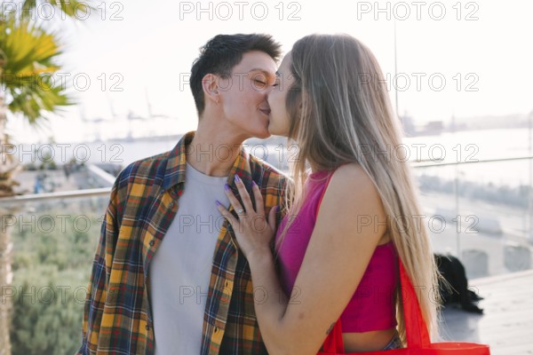 A happy lesbian couple shares a moment of love outdoors while kissing, celebrating diversity and