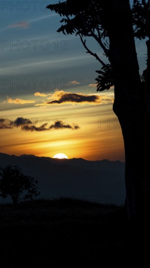 Captivating scene of the sun setting behind the silhouetted mountains, viewed from a vantage point