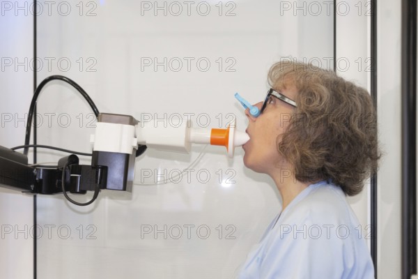 A woman is shown with nose clip performing a spirometry test to assess her lung function in a