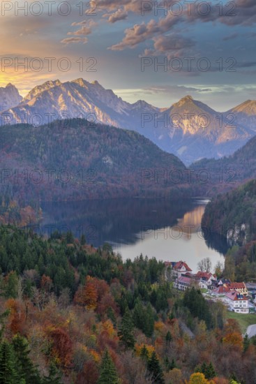 A picturesque view of a village nestled near a serene lake, surrounded by autumn foliage and the