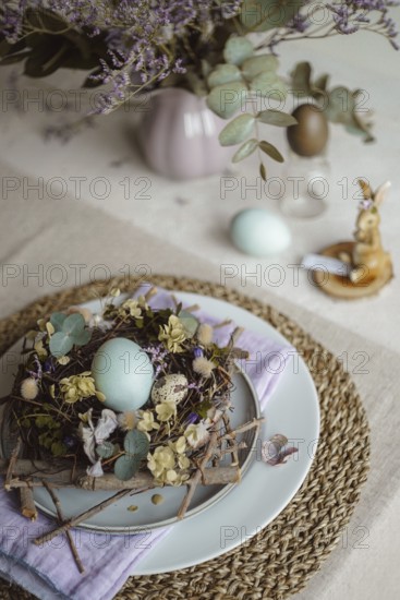 Top view of an Easter table setting featuring a plate with a rustic nest of twigs and naturally